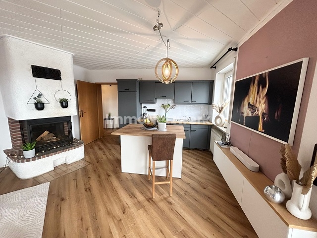 Wohnzimmer mit Kamin und offener Küche